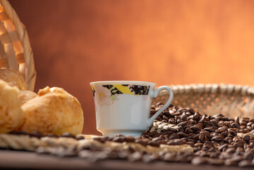 Cheese bread and coffee, delicious Brazilian cheese bread and a beautiful cup of coffee on a rustic table and coffee beans, abstract background, selective focus.