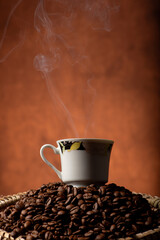 Coffee, beautiful cup of coffee on a heap of coffee beans in a straw sieve, abstract background, selective focus.