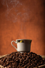 Coffee, beautiful cup of coffee on a heap of coffee beans in a straw sieve, abstract background, selective focus.