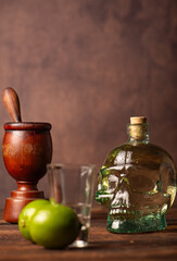 Cachaça from Brazil, bottle of cachaça from Brazil in the shape of a skull, lemon accessories on rustic wood and abstract background, low key photo, selective focus.