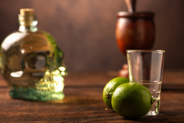Cachaça from Brazil, bottle of cachaça from Brazil in the shape of a skull, lemon accessories on rustic wood and abstract background, low key photo, selective focus.