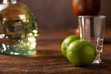 Cachaça from Brazil, bottle of cachaça from Brazil in the shape of a skull, lemon accessories on rustic wood and abstract background, low key photo, selective focus.