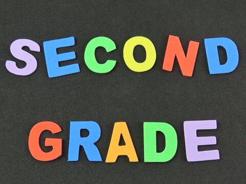 Multicolored eva foam letters form the expression "Second grade", referring to the elementary school days. Black background. Back to school concept.