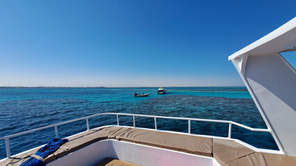 Scenic view from a yacht showcasing vibrant turquoise waters, with boats anchored nearby, highlighting the beauty of marine landscapes and leisure activities. Red Sea. Hurghada. Egypt