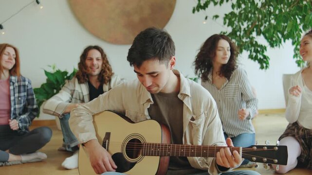 Group of friends enjoying a cozy music jam session indoors with a guitar on a sunny afternoon surrounded by plants