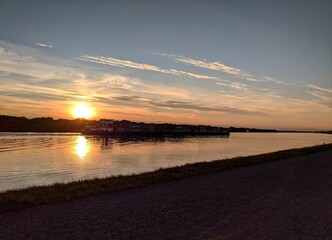 Sunset over river with cargo ship and colorful sky reflections