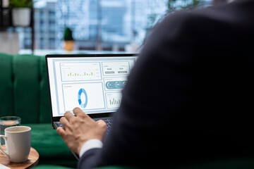 Confident business leader reviews sales trends and budget reports in his smart office, ensuring...