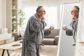 Mature man in a bathrobe using face cream