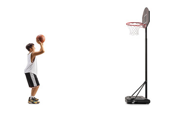 Full lenggth profile shot of a teenage boy shooting a basketball in a hoop