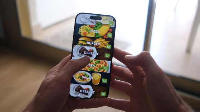 Male hands holding phone with food delivery app on screen against background of room in house