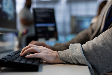 Close up of engineer implementing cybersecurity measures to protect data center assets and information. Man typing on keyboard in server hub, monitoring metrics to enhance operational effectiveness