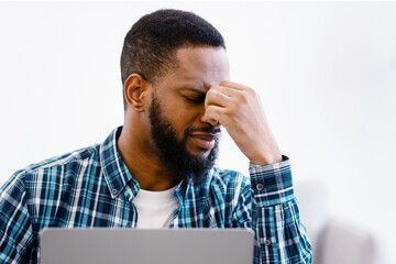 Eyes Fatigue. Tired Black Guy Massaging Nosebridge Holding Eyeglasses After Work On Laptop Computer...