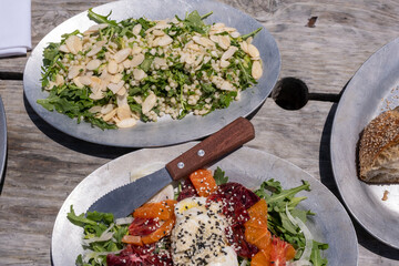 Shared burrata salad bowl with citrus fruit, arugula greens, and wood utensils on a stone table in Burlingame, CA