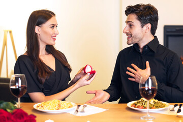 Will You Marry Me. Smiling millennial woman proposing to her boyfriend, holding and showing open...