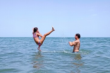 father and daughter are having fun.Girl jumps in to the water . High quality photo