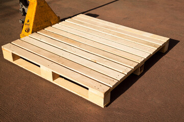 Empty wooden pine pallet with a pallet truck or transpallet in front of a warehouse, logistics and industrial transportation