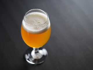 Unfiltered beer glass on dark table with copy space