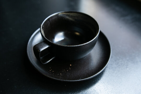 a black empty cup stands on a saucer