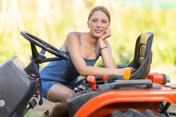 Obraz premium Young woman farmer in dress posing near tractor in countryside
