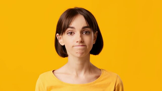 A young woman with brunette hair displays a neutral expression while shrugging with her shoulders. The vibrant background enhances her contemplative demeanor, creating a striking visual contrast.