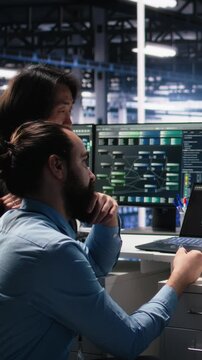 Vertical video Data center software developers using machine learning algorithms to analyze large datasets. Server hub IT experts cooperating, using AI neural networks to recognize data patterns