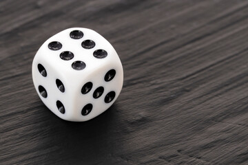1 white dice with black dots in a row on a dark table