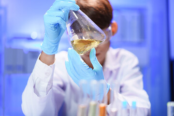 A young male scientist examining a in beaker a lab.