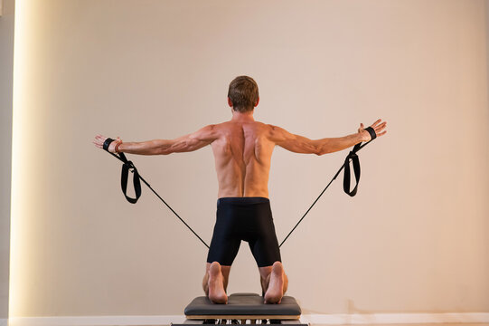 A man doing Pilates on a reformer.  - Powered by Adobe