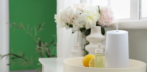 Tray with air humidifier, essential oil and lemons on table in room