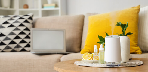Air humidifier with essential oils and lemon on table in living room, closeup