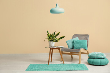 Interior of room with chair, poufs, table and sansevieria plant near beige wall