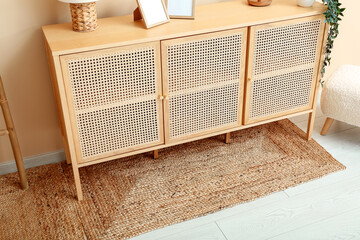 Chest of drawers with blank pictures and wicker rugs in living room