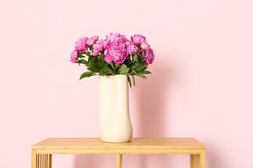 Vase of pink peonies on shelving unit near color wall