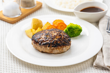 白いテーブルにハンバーグとライスの洋食セット
