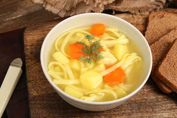 Bowl of tasty chicken soup on wooden background