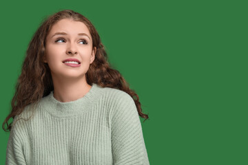 Portrait of ashamed young woman on green background