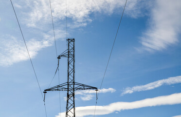 Clear view of a metal electricity transmission tower standing tall amid a blue sky with wispy clouds