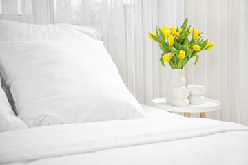 Vase of yellow tulips on bedside table in bedroom