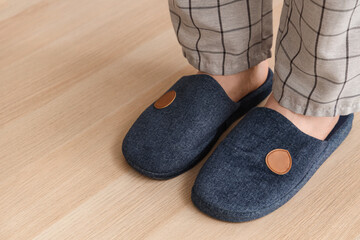 Male legs in warm blue slippers on laminate floor, closeup