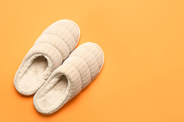 Pair of beige soft slippers on orange background. Top view