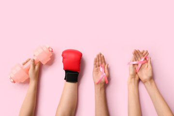 Female hands with pink ribbons, dumbbell and boxing glove on color background, closeup. Breast...