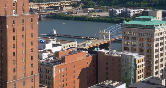 A high angle long shot view of a coal barge traveling under the Smithfield Street Bridge on the Monongahela River in Pittsburgh, Pennsylvania.  	