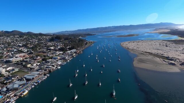 A banking forward aerial view over Morro Bay Yacht Club and the Morro Bay Marina in southern California. Helicopter GoPro footage. Longer segments available upon request.  	