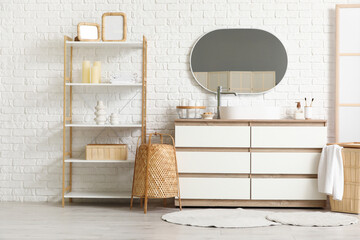 Chest of drawers and shelving unit near white brick wall in interior of bathroom