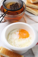 Half-boiled egg in bowl, tea and toasted bread on white marble table, closeup. Traditional asian breakfast