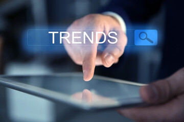 Businessman using tablet computer to find hot tendencies, new ideas, popular directions, closeup. Search bar with word Trends