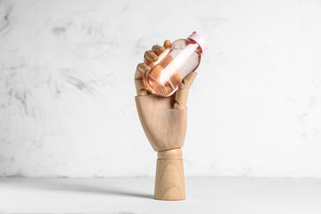 Wooden hand with bottle of micellar water on white table