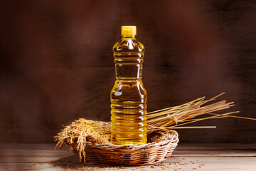 Vegetable oil extracted from rice grains is packed in glass or plastic bottles with golden yellow rice grains, an agricultural product.