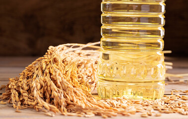 Vegetable oil extracted from rice seeds is packed in glass or plastic bottles with golden yellow rice seeds, which are an agricultural product. Close-up photo.