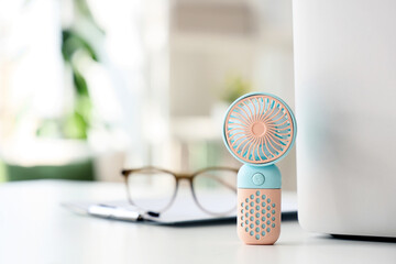 Small electric fan on table in office